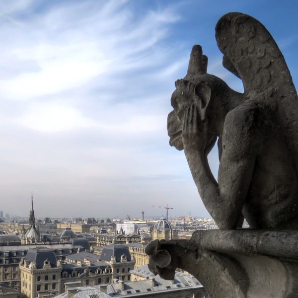 Chimera on Notre Dame de Paris overlooking the city on a sunny day