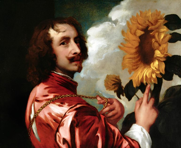 Artist in a richly-dyed pink coat, looking over his shoulder while gesturing toward a large sunflower with his right hand and pointing to a gold chain with his left