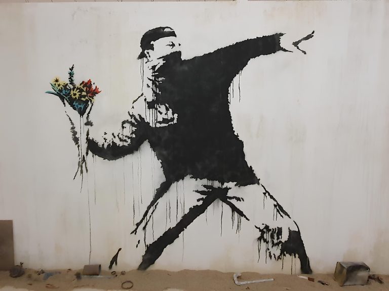 A masked protester poised to throw a bouquet of flowers rather than a weapon
