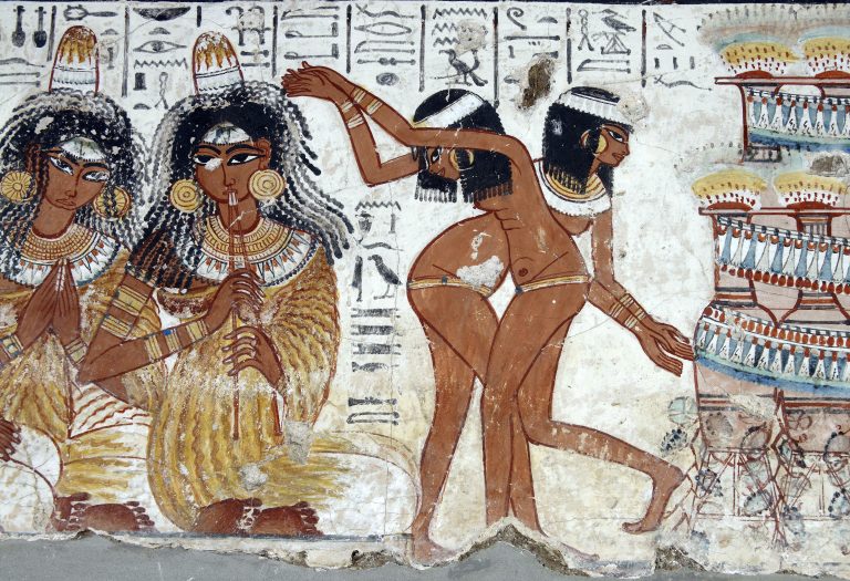 Two musicians (shown full-face) are shown seated on the ground while two dancers provide entertainment for the guests. The dancers wear girdles, ear-rings