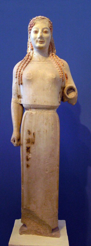 A stiff, frontal pose, wearing a distinct garment once mistaken for a peplos, but likely a goddess’s attire