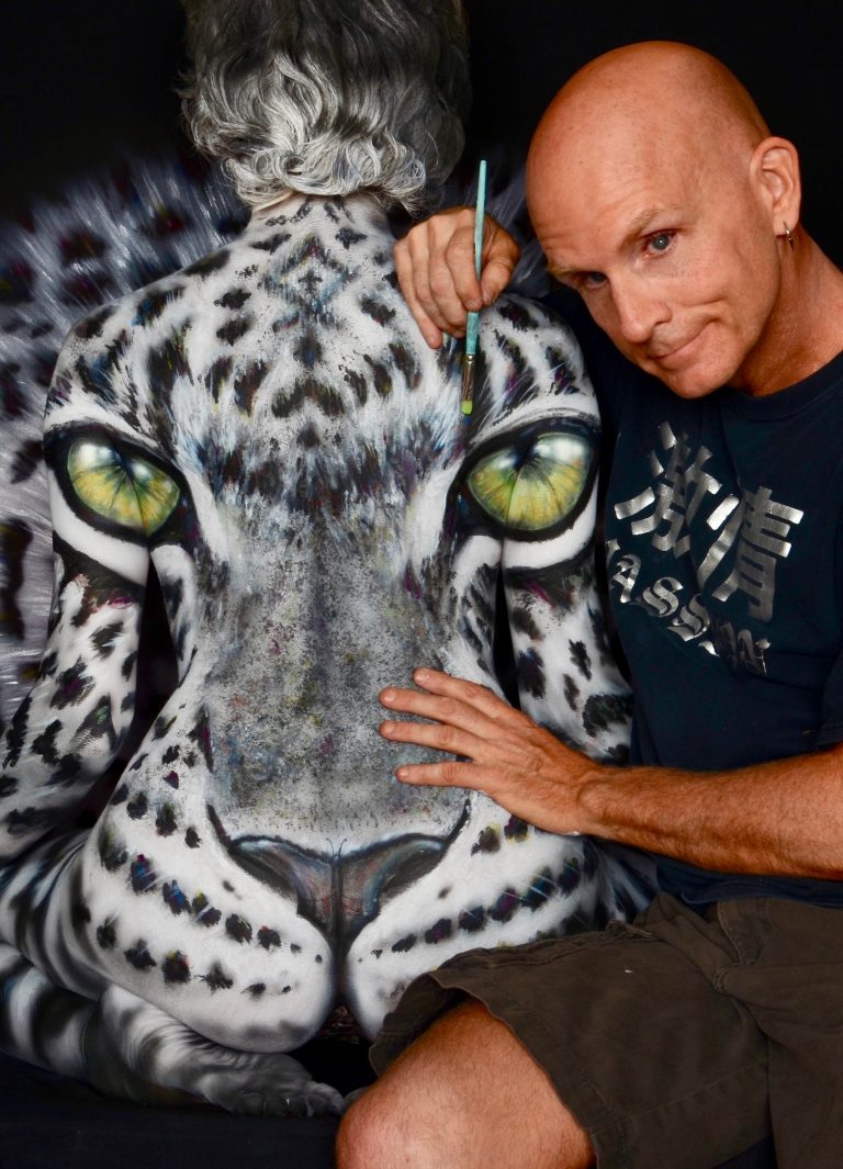 photographic bodypainting composition where nude female model’s body is fully painted and arranged so their forms merge into a single animal-like image, with the human bodies visually concealed within the overall composition.